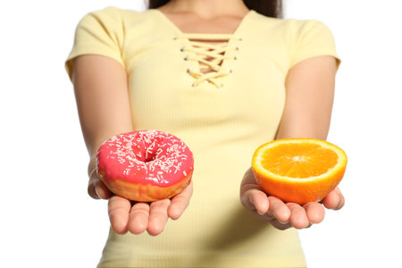 concept of choice. Woman holding orange and donut on white background, closeupの写真素材