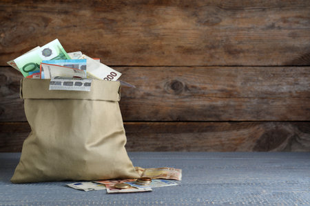 Sack full of money on wooden table. Space for textの写真素材