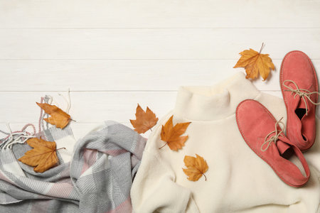 Flat lay composition with sweater and dry leaves on white wooden background, space for text. autumn seasonの写真素材
