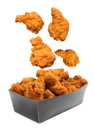Fresh fried chicken falling into container on white backgroundの写真素材