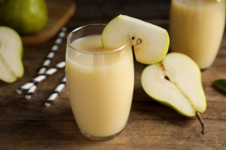 Fresh pear juice in glass and fruits on wooden table, closeupの写真素材