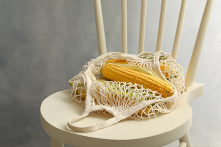 Bag of corn cobs on chair against gray backgroundの写真素材