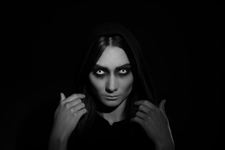 Mysterious witch with spooky eyes on dark background. black and white effectの写真素材