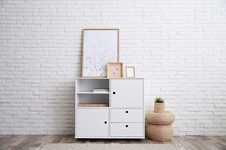 Modern white cabinet near brick wall in room. interior design