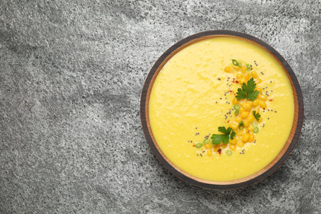 Delicious creamy corn soup on gray table, top view. Space for text