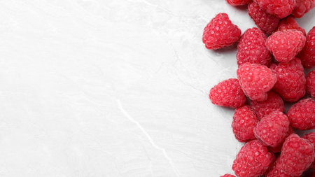 Delicious fresh ripe raspberries on light marble table, flat lay. Space for text