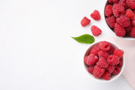 Delicious fresh ripe raspberries on white table, flat lay. Space for textの写真素材