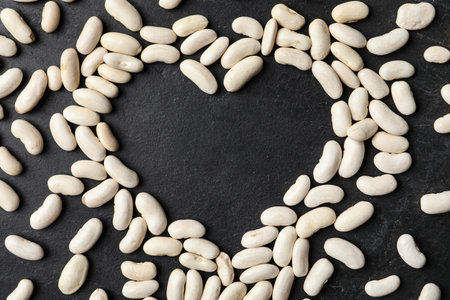 Heart shaped frame made of raw beans on black background, flat lay with space for text. vegetable...