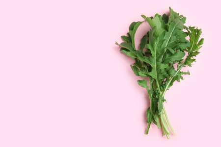 Fresh arugula on light pink background, flat lay. Space for textの写真素材