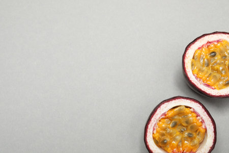 Halves of fresh ripe passion fruit (maracuya) on gray background, flat lay. Space for textの写真素材