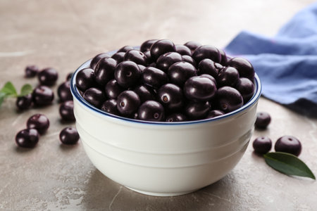 Fresh acai berries in bowl on light marble table, closeup