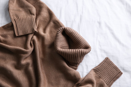 Brown warm sweater on white crumpled fabric, top viewの写真素材