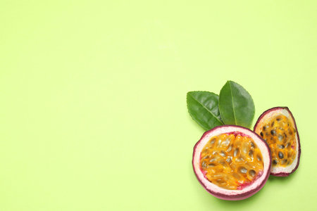 Slices of fresh ripe passion fruit (maracuya) with leaves on light green background, flat lay. Space for textの写真素材