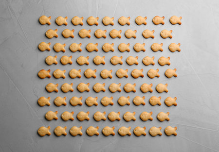 Delicious goldfish crackers on gray table, flat lay