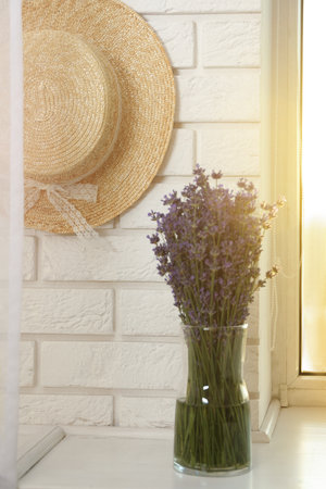 Beautiful lavender bouquet and straw hat near window indoorsの写真素材