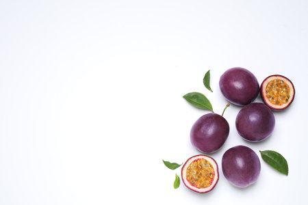 Fresh ripe passion fruits (maracuyas) with leaves on white background, flat lay. Space for textの写真素材