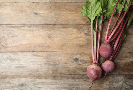 Raw ripe beets on wooden table, flat lay. Space for text