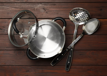 Modern saucepan, skimmer and spoon on brown wooden table. Cooking utensilsの写真素材