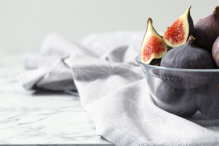 Whole and cut tasty fresh figs on white marble table, closeup. Space for text
