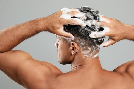Handsome man washing hair on gray background, back viewの写真素材