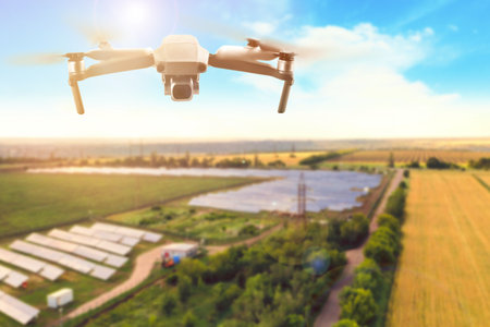 Modern drone flying over fields on sunny day. Aerial survey