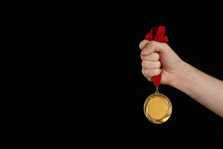 Man holding gold medal on black background, closeup. space for designの写真素材