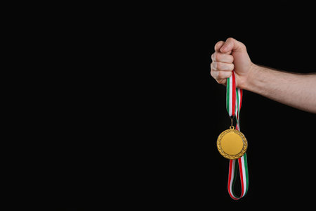 Man holding gold medal on black background, closeup. space for designの写真素材