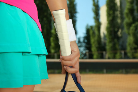 Sportswoman with racket at tennis court on sunny day, closeupの写真素材