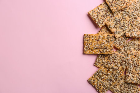 Delicious crackers on pink background, flat lay. Space for text