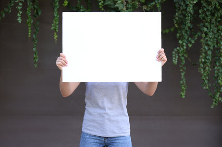 Woman holding blank poster outdoors. Mockup for designの写真素材