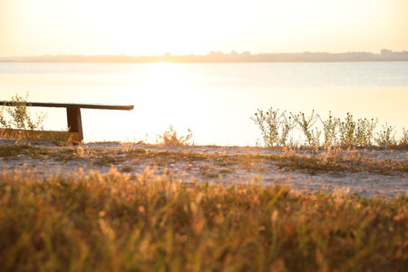 Wooden bench near the river at sunrise. early morning landscape
