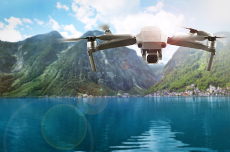 Modern drone flying over lake near picturesque mountains. Aerial survey