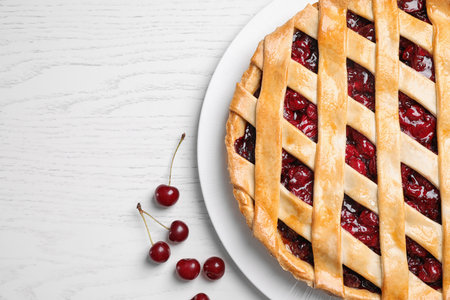 Delicious fresh pie and cherries on white wooden table, flat lay. Space for textの写真素材