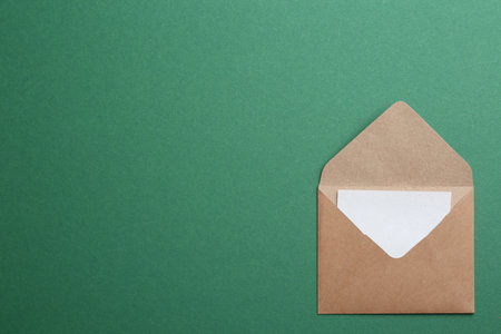 Brown paper envelope on green background, top view. Space for textの写真素材