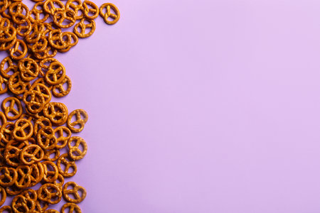 Delicious pretzel crackers on violet background, flat lay. Space for textの写真素材
