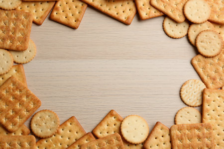 Frame of delicious crackers on wooden table, flat lay. Space for textの写真素材