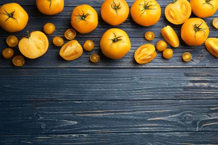 Ripe yellow tomatoes on blue wooden table, flat lay. Space for textの写真素材