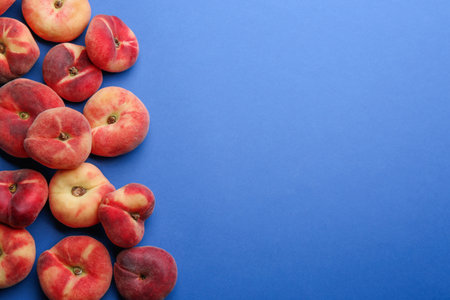 Fresh donut peaches on blue background, flat lay. Space for text
