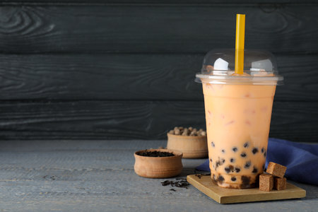 Tasty brown milk bubble tea in plastic cup on light blue wooden table. Space for textの写真素材