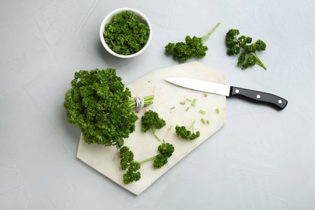 Fresh curly parsley, cutting board and knife on light gray table, flat layの写真素材