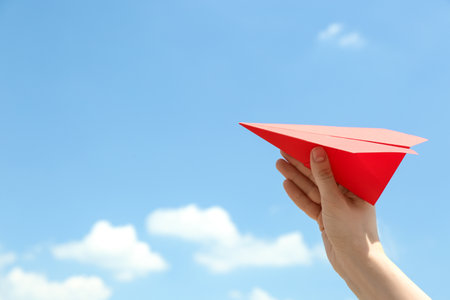 Woman holding paper plane against blue sky, closeup. Space for textの写真素材