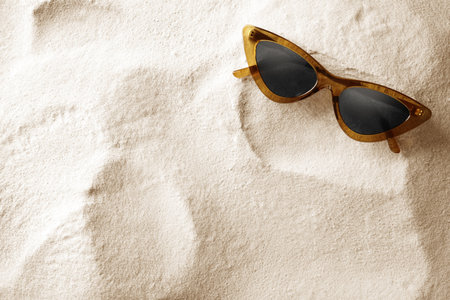 Stylish sunglasses on white sand, top view. Space for textの写真素材