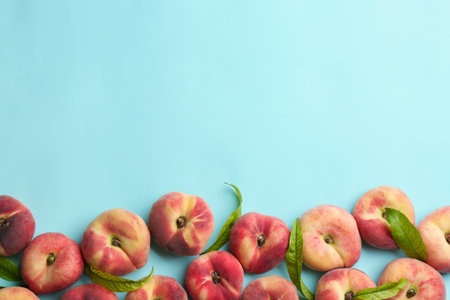 Fresh donut peaches on light blue background, flat lay. Space for text
