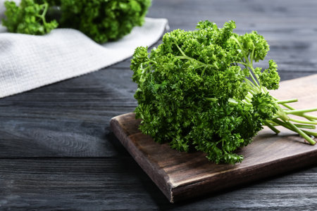 Fresh curly parsley and cutting board on black wooden table. Space for textの写真素材