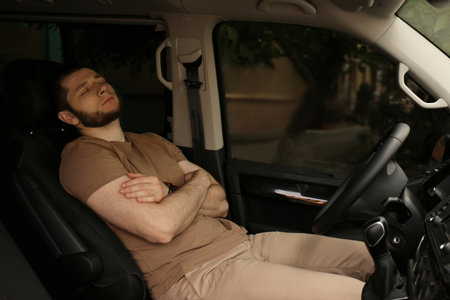 Tired man sleeping in his modern carの写真素材