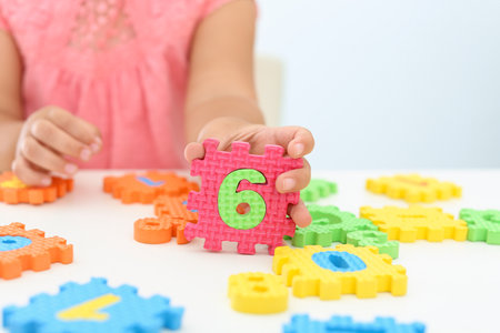 Little girl playing with colorful puzzles at white table, closeup. educational toyの写真素材
