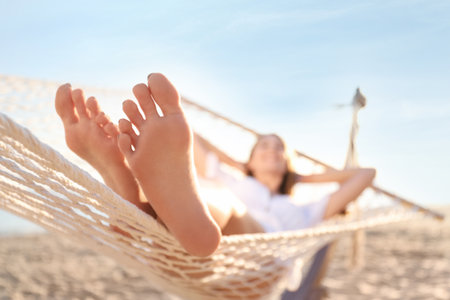 Young woman relaxing in hammock outdoors, focus on legsの写真素材