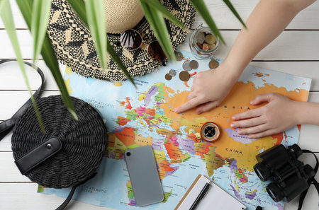 Woman with world map and accessories at table, top view. Travel during summer holidaysの写真素材