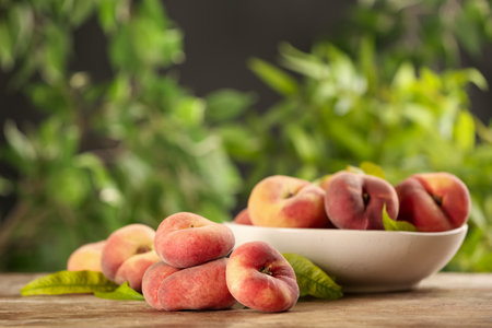Fresh ripe donut peaches on wooden table against blurred green background. Space for textの写真素材