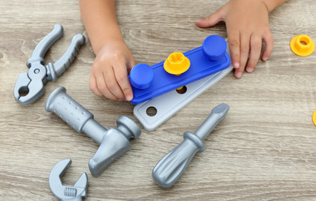 Little boy playing with toy construction tools at wooden table, closeupの写真素材